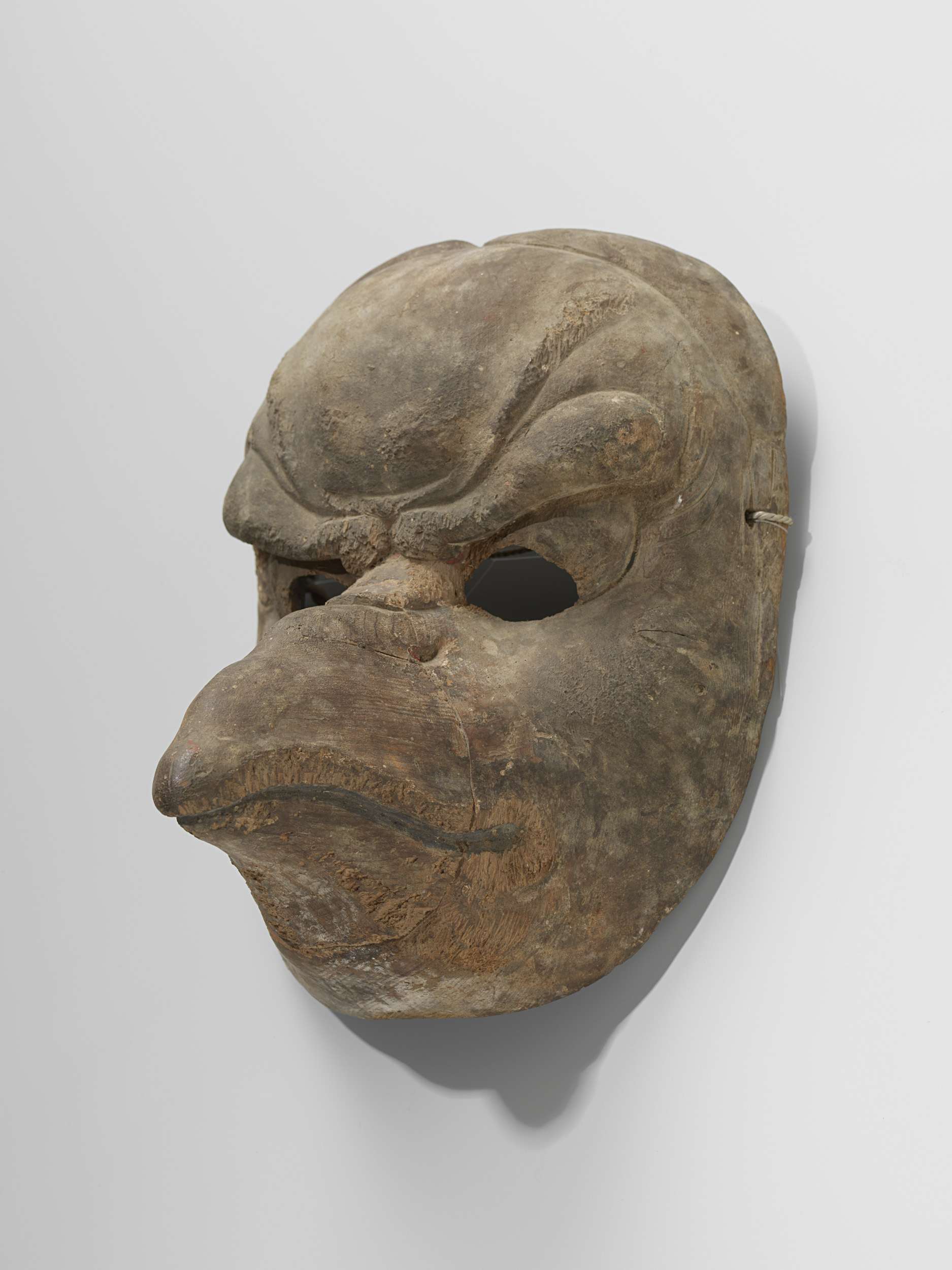 Figurative wood sculpture of a masked face by Unknown Artist