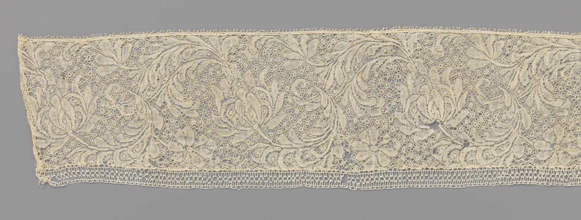 Lace artwork by Unknown Artist depicting a flower and C-shaped leaf.