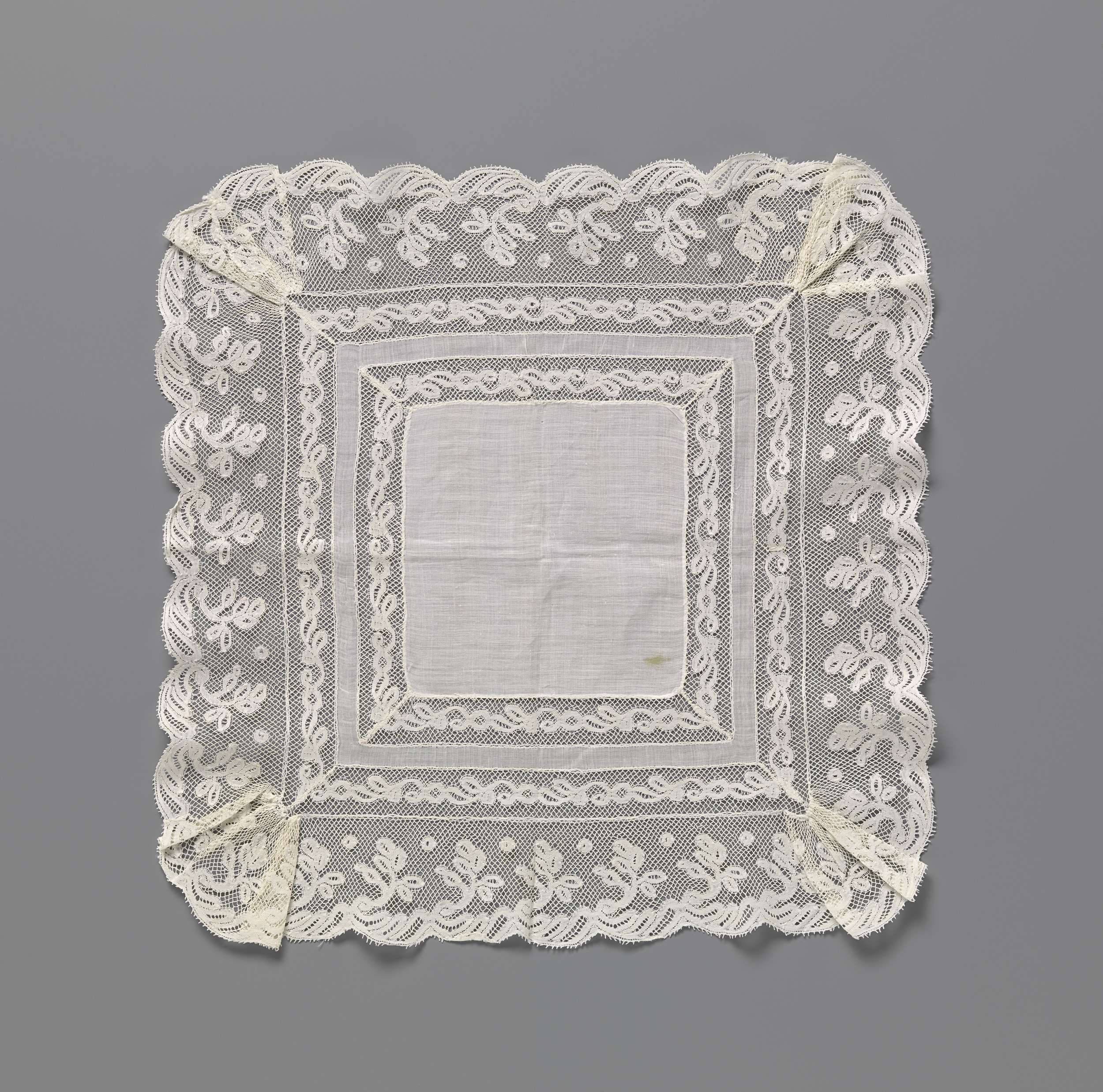 Delicate lace handkerchief by Unknown Artist, featuring intricate C-shaped vine patterns.
