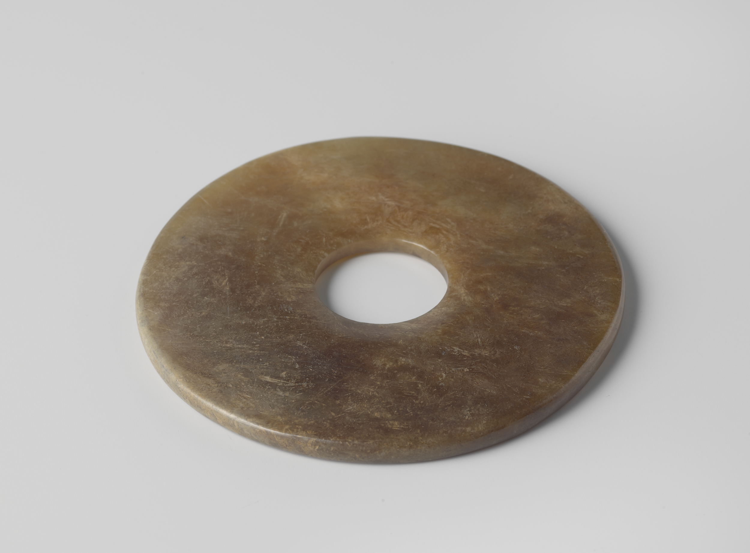 Brown jade disc by Unknown Artist, showcasing ancient craftsmanship