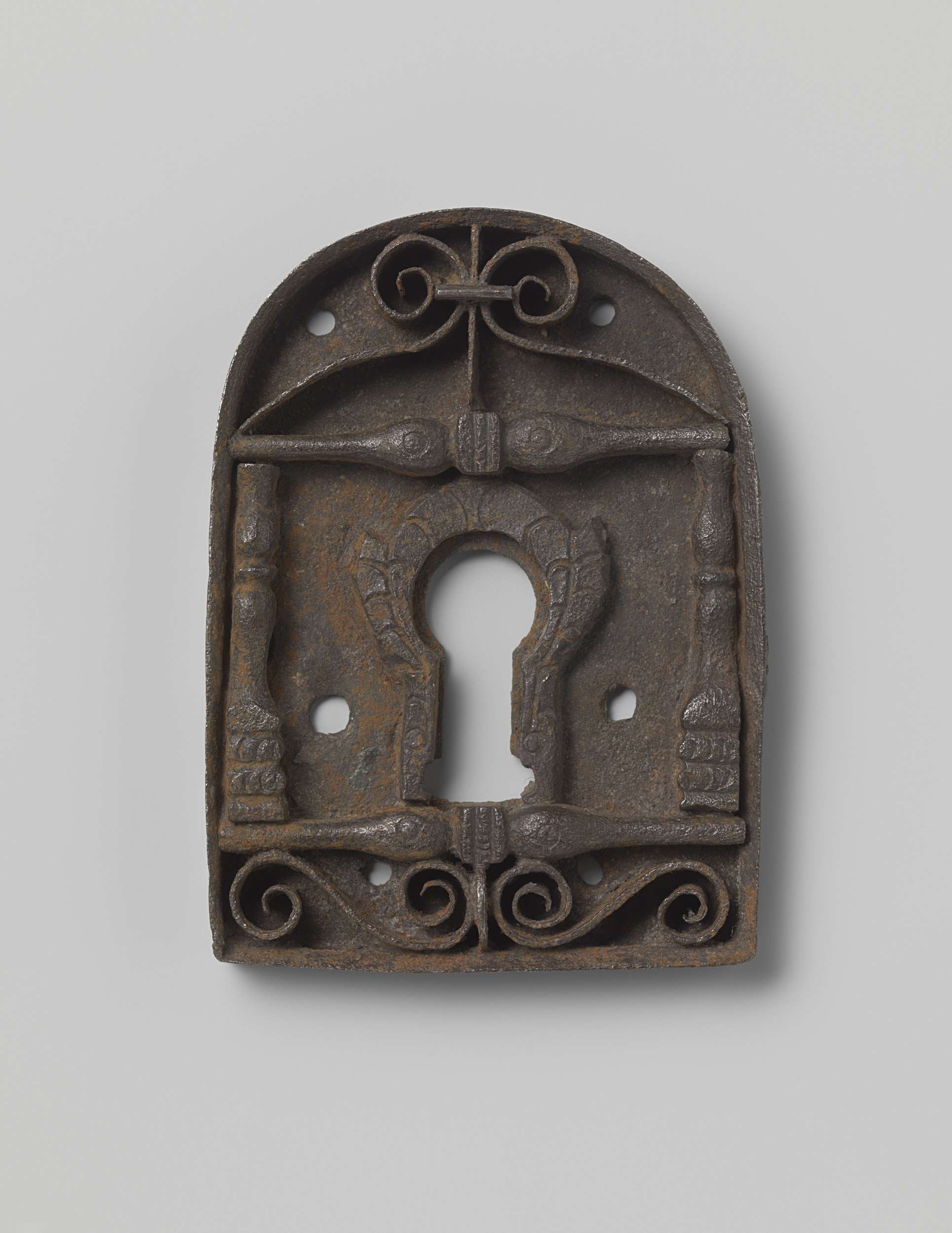 Decorative metal key plate by anoniem, featuring intricate details and a keyhole.
