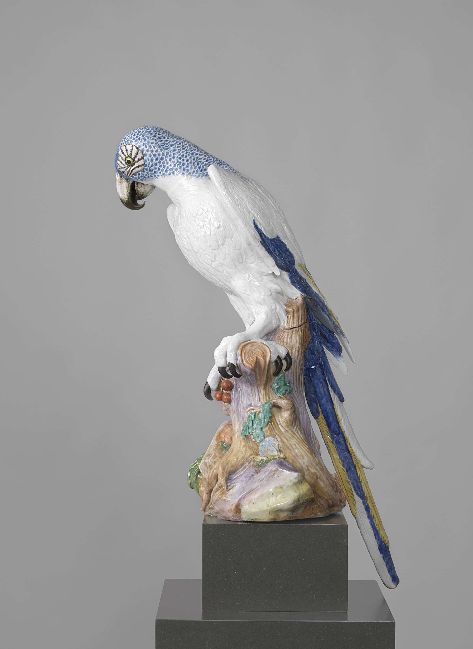 Porcelain Blue Parrot by Meissener Porzellan Manufaktur, perched on a tree stump with cherries.