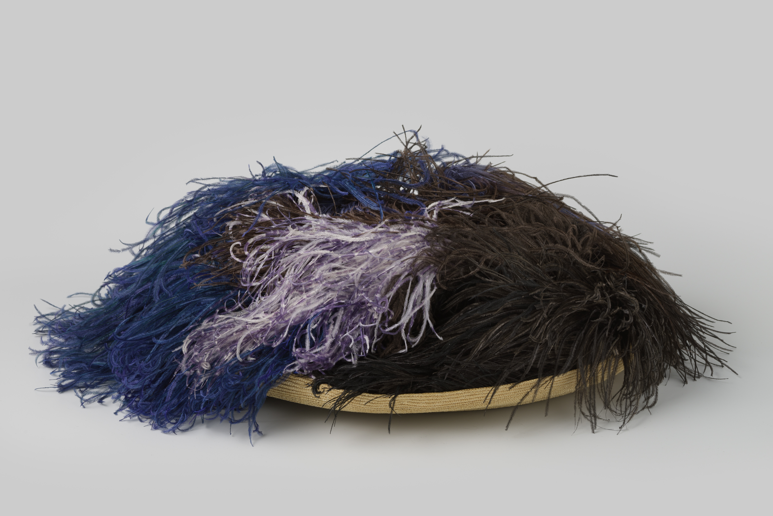 Still life featuring a straw hat with colorful feathers by Unknown Artist