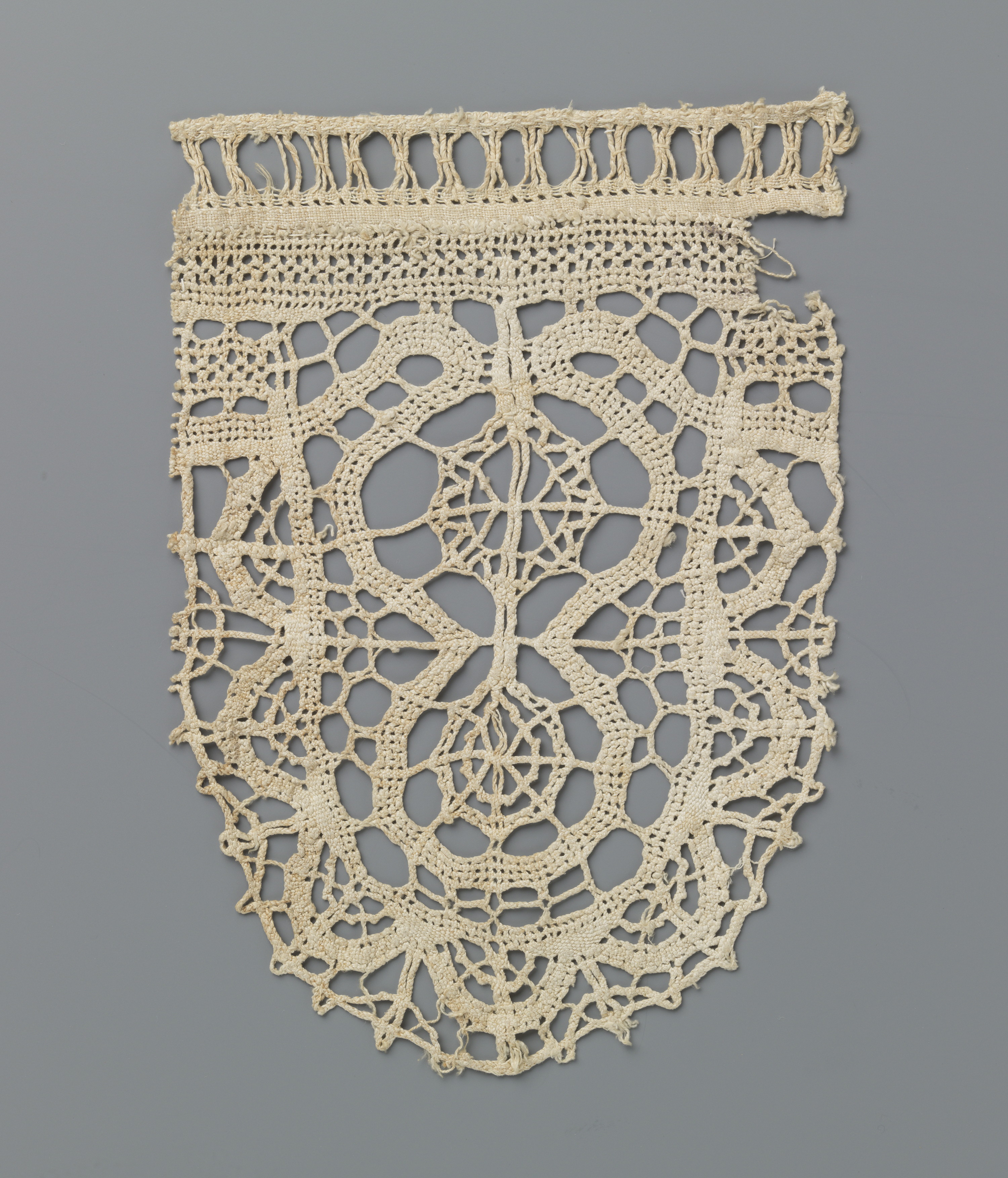 Lace fragment featuring a shell and two wheels by Unknown Artist