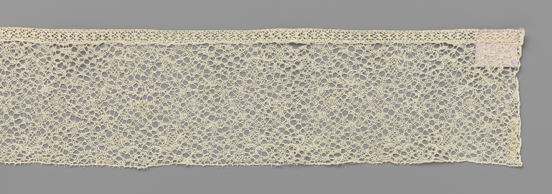 Intricate lace textile by Unknown Artist, featuring swirling floral motifs.