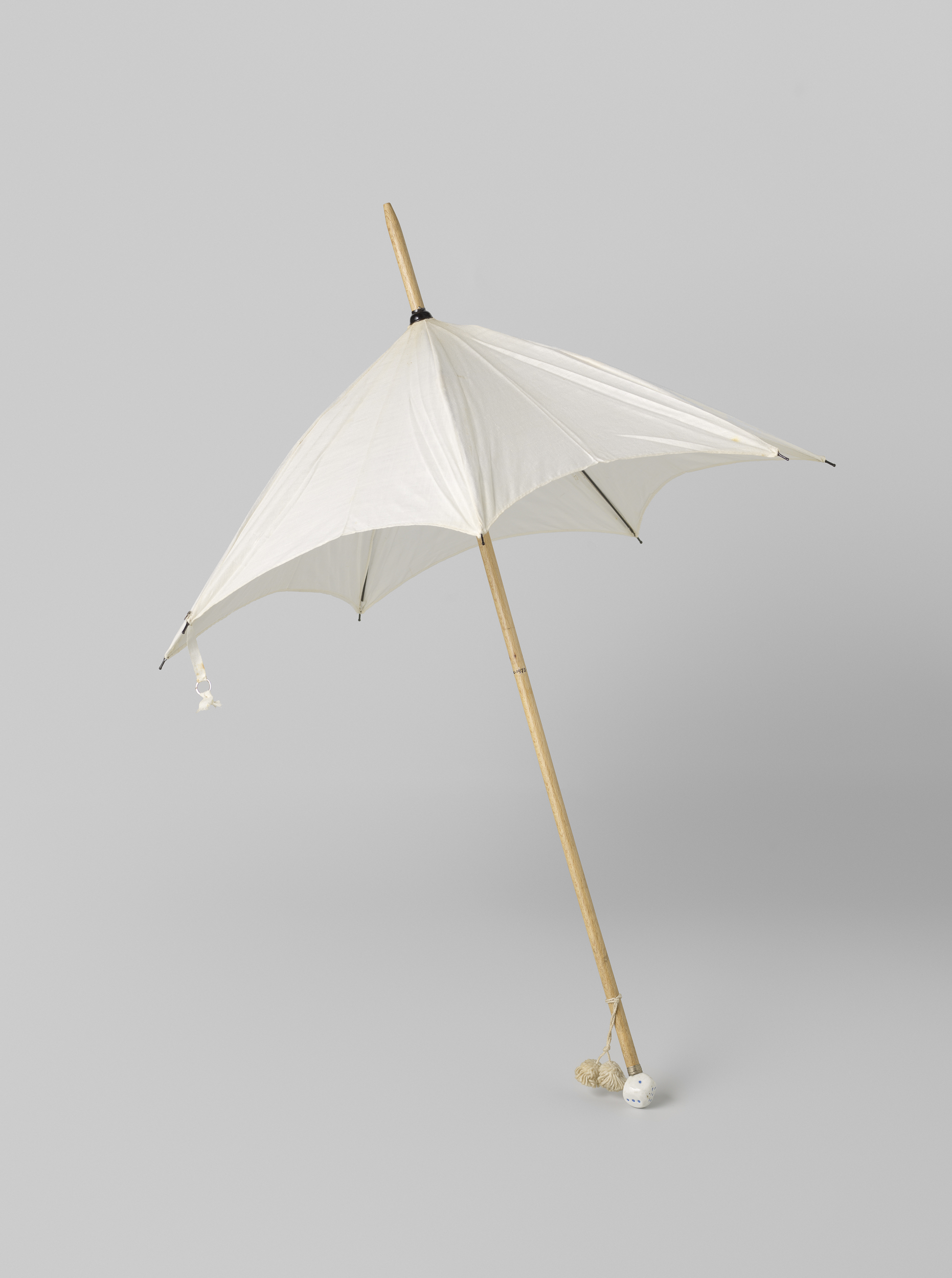 Still life featuring a parasol with white fabric and blue dots by Gustav Schnitzler