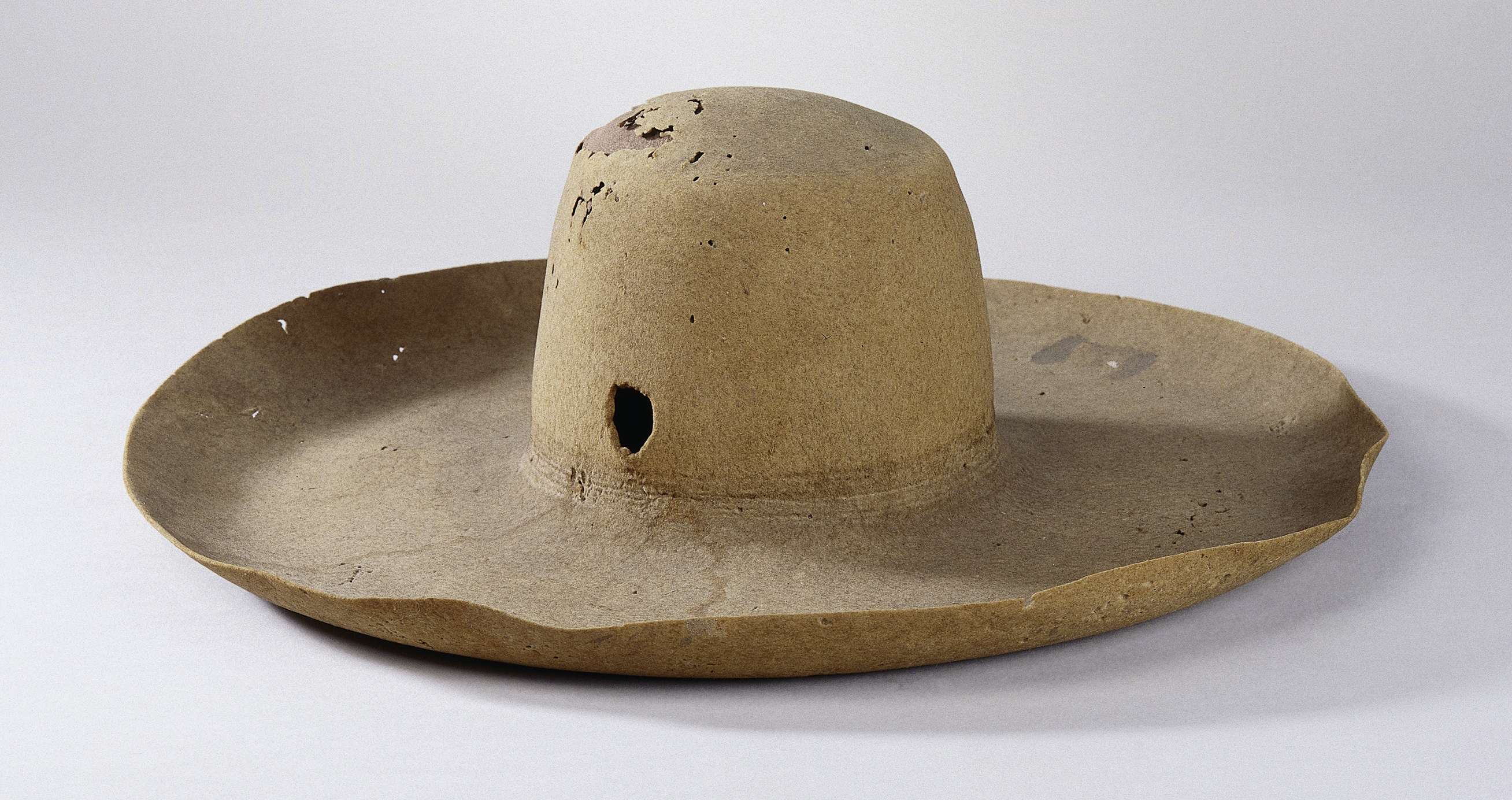 Still life of a textile hat with a bullet hole by an unknown artist