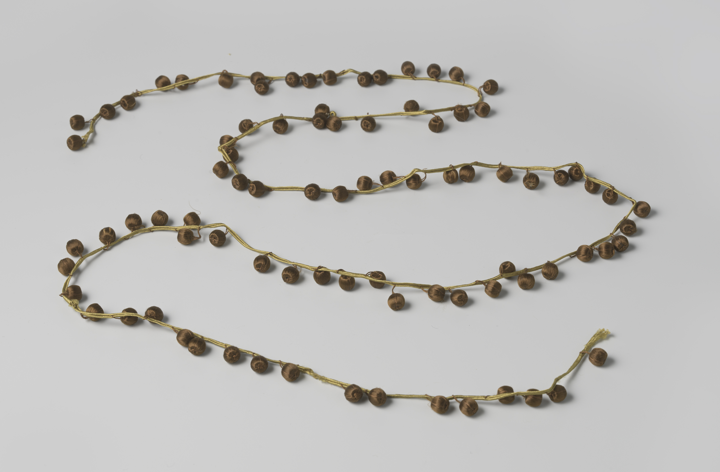 Decorative art by Gustav Schnitzler featuring golden galon with brown silk pompons.