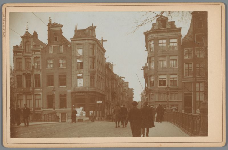 Landscape photograph by Gebr. van R. showing a street in Amsterdam with cobblestones and buildings.
