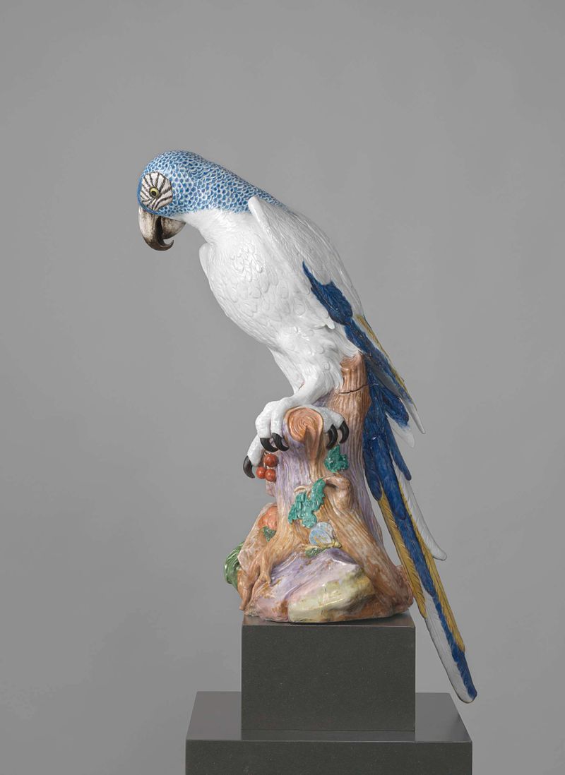 Papagaio de porcelana Blue Parrot de Meissener Porzellan Manufaktur, empoleirado em um tronco com cerejas.