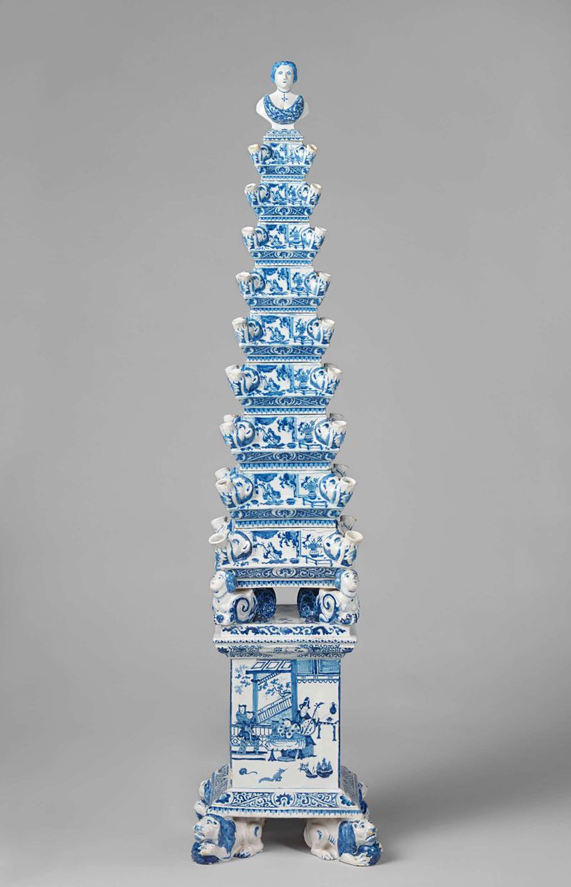 Flower pyramid in paint by De Metaale Pot, featuring a tall stacked vase with flowers.