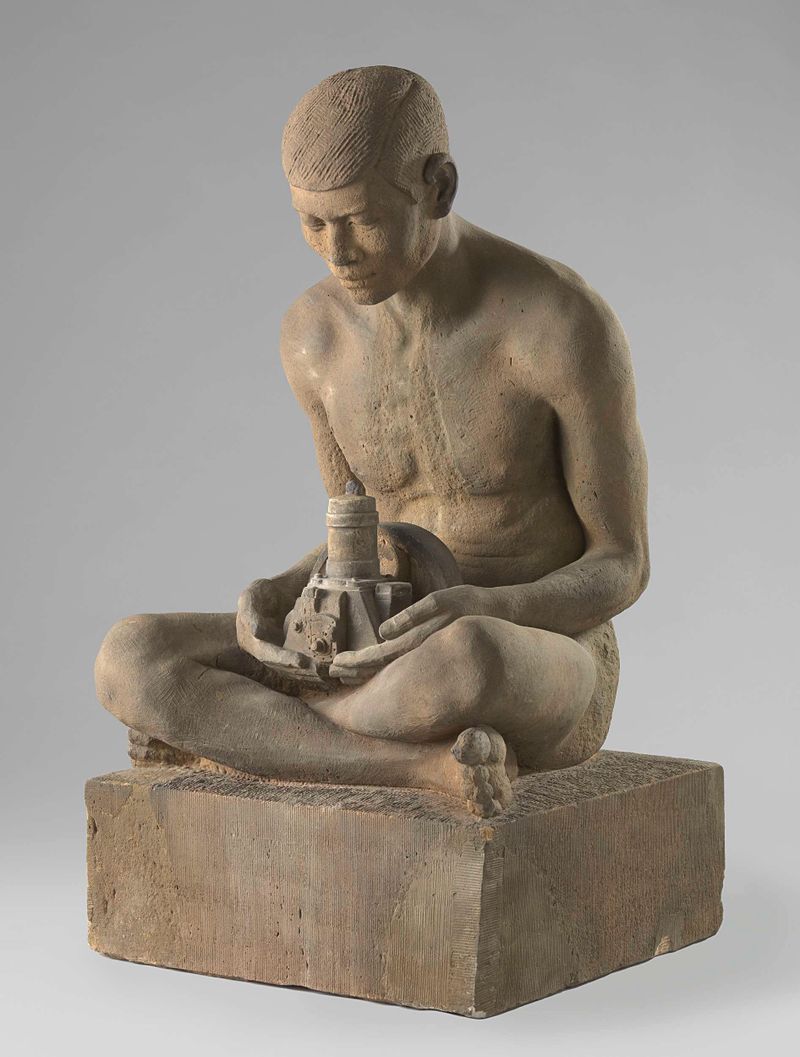 Escultura de Marinus Johannes Hack representando um homem javanês nu com uma máquina, em pedra.