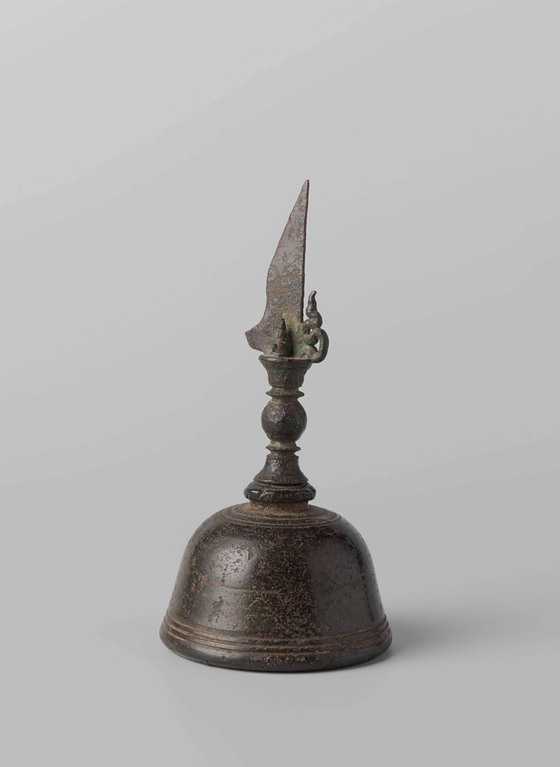 Campana de mano de bronce en reposo, reflejando luz y sombras, de Artista Desconocido
