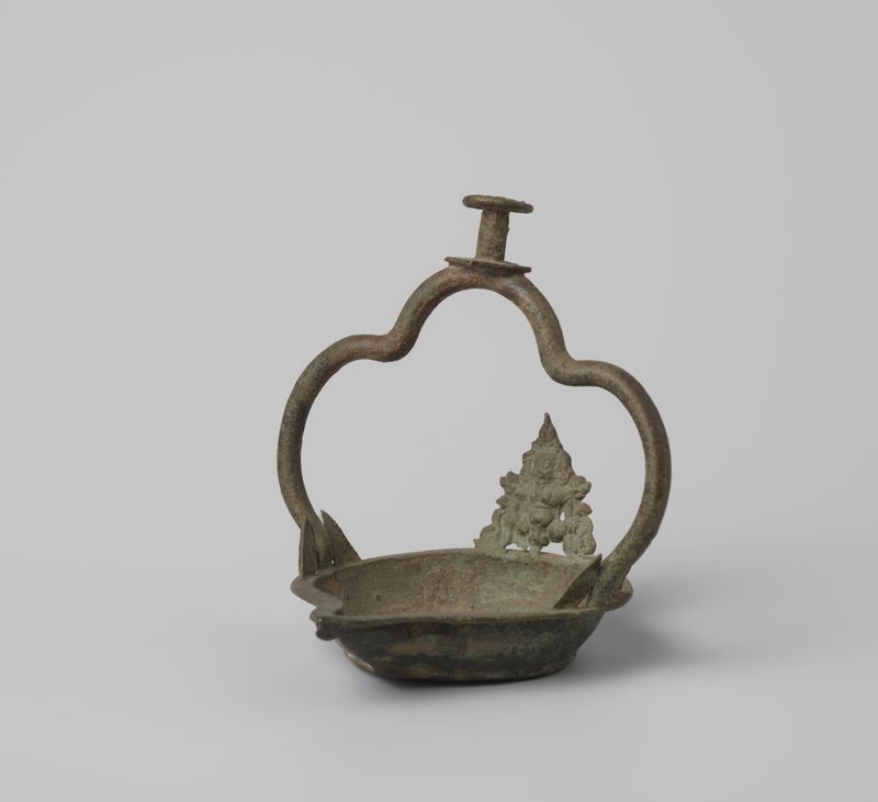 Lámpara de bronce de un artista desconocido, mostrando detalles intrincados y luz cálida.